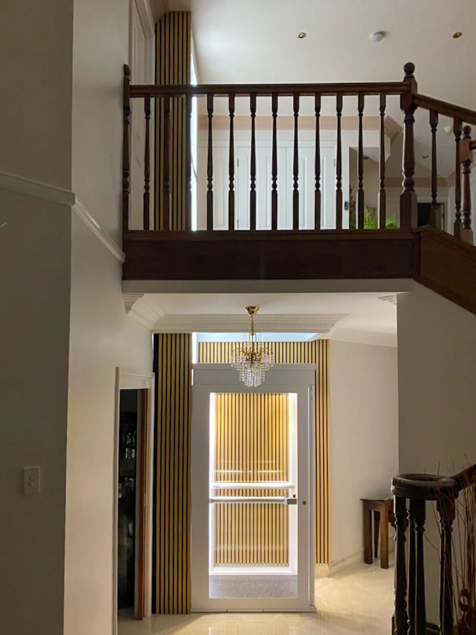 Lift rumah Ascenda 2 lantai dengan shaft putih dan panel kaca pada interior rumah modern cluster BSD