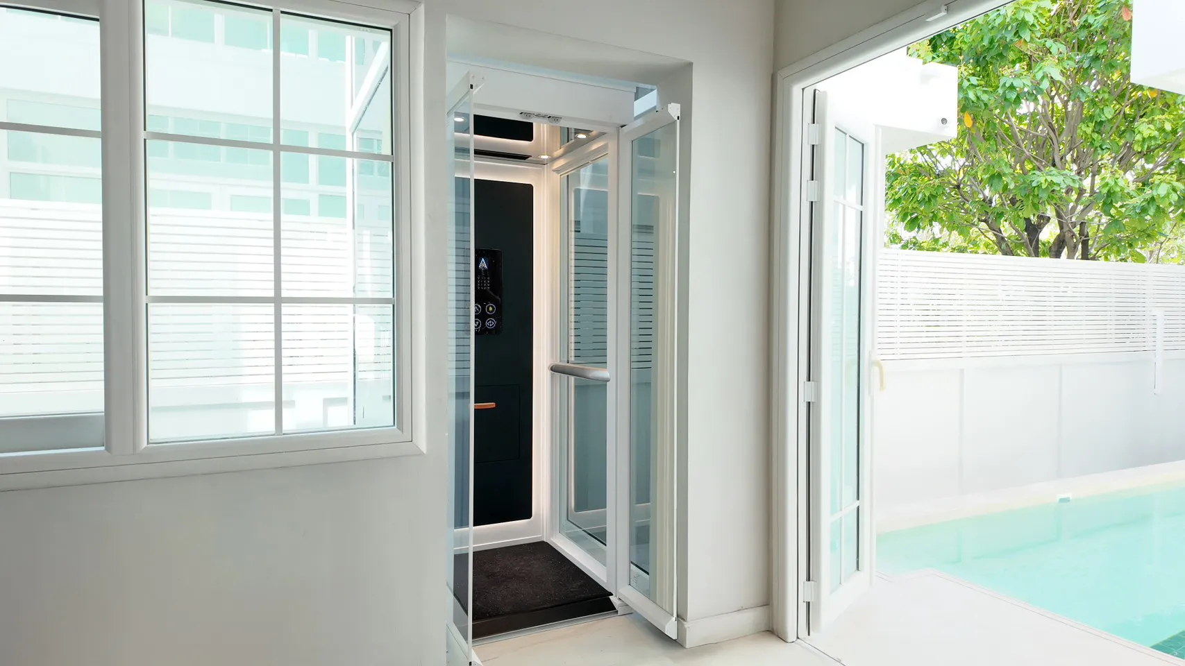 Mencari Outdoor Lift? Kenali Solusi Lift Rumah Semi-Outdoor yang Tepat 16 Lift rumah Ascenda dengan shaft kaca dan pintu swing terpasang di area semi-outdoor dekat kolam renang.