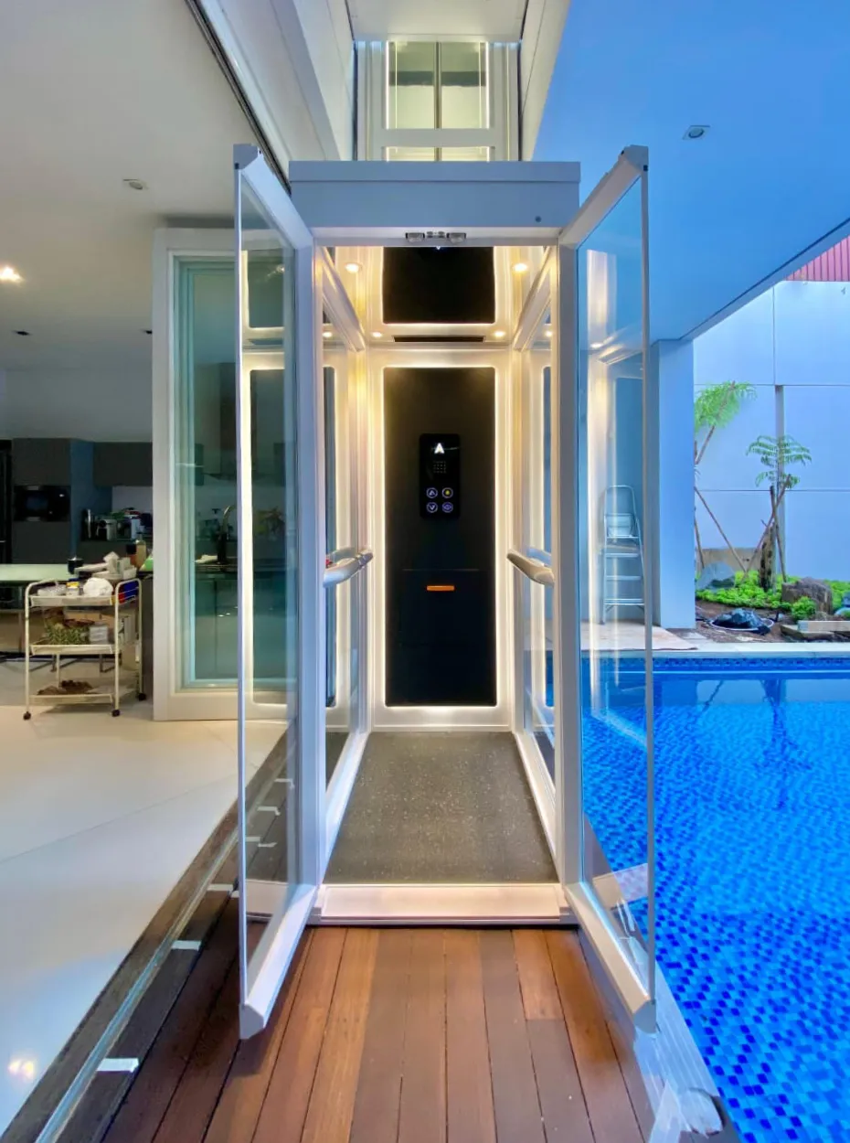 Mencari Outdoor Lift? Kenali Solusi Lift Rumah Semi-Outdoor yang Tepat 15 Tampak samping lift rumah Ascenda dengan shaft kaca yang terpasang di samping kolam renang dan area teras.