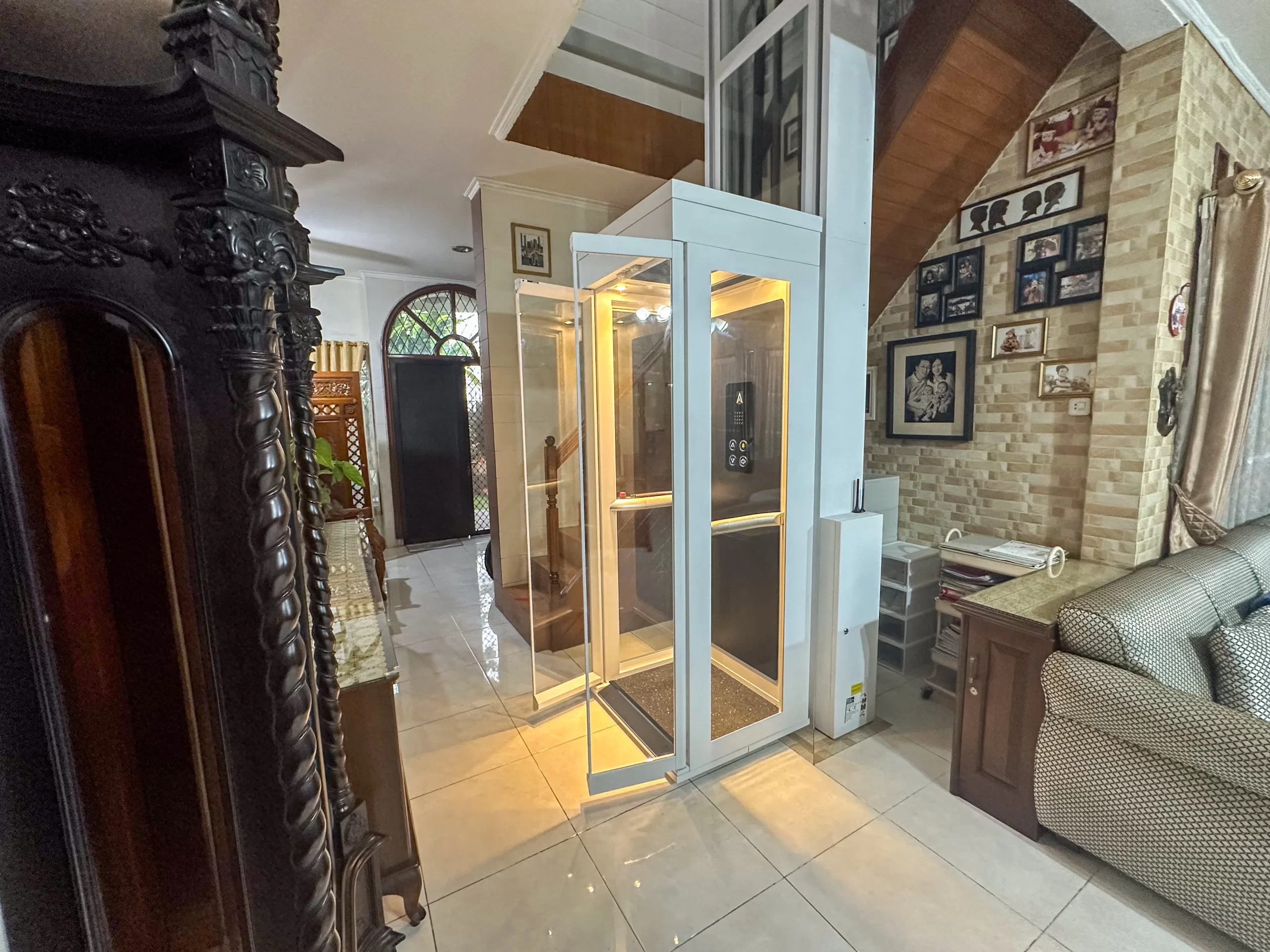 Lift Rumah Terkecil di Indonesia | Ascenda Size S 5 Lift rumah kecil Ascenda Size S dengan pintu kaca terbuka di ruang keluarga rumah 2 lantai.